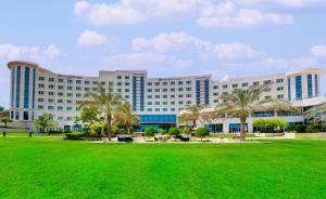 un grande edificio con palme di fronte di Crowne Plaza Muscat OCEC by IHG a Mascate