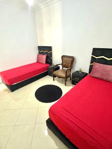 a bedroom with two red beds and a chair at A modern apartment in Fès