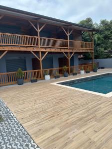 a house with a wooden deck and a swimming pool at Logement avec piscine a 50 metre de la mer in Cayenne