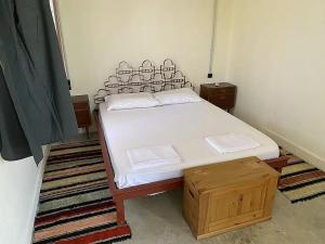 une chambre avec un lit avec des draps blancs et une boîte en bois dans l'établissement Alyki Heritage Hotel - Αλυκή Τουριστικές Επιχειρήσεις ΙΚΕ, à Alykí