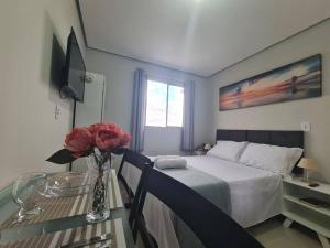 a bedroom with a bed and a table with a vase of flowers at Kitnet304 centro,c linda vista janela, tv smart in Montes Claros