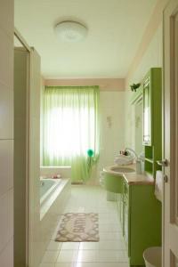 Un baño verde con bañera, lavabo y un tubo. en Raggio di sole, oasi di felicità, en Monsagrati