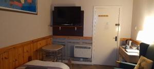 a room with a kitchen with a television and a stool at Bannockburn Inn in Helmsdale