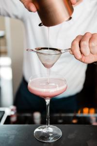 a person pouring a cocktail into a martini glass at Hotel A'mare in Zadar