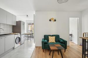 a living room with a green chair and a kitchen at Duplex apartment downtown with parking in Cergy