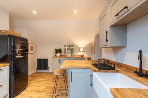 a kitchen with white cabinets and wooden floors at The Loft at Goytre Hall in Abergavenny