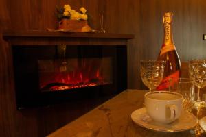 a bottle of wine and a cup on a table with a fireplace at Dworek Biała Dama Klimatyczne Pokoje in Gniezno