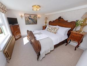 a bedroom with a large bed and a television at Quaint 18th Century Cottage in Lymington in Lymington