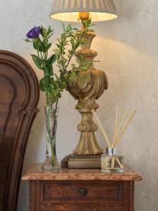 a table with a lamp and vases with flowers on it at Quaint 18th Century Cottage in Lymington in Lymington