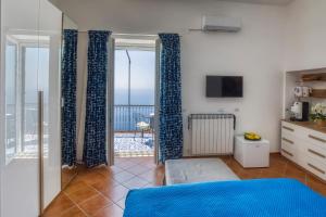 a bedroom with blue curtains and a view of the ocean at Salvo's House in Furore