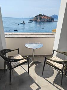 a balcony with a table and chairs and a view of the water at Serenity at Sveti Stefan in Sveti Stefan