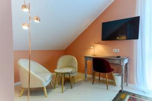 a room with chairs and a desk with a tv on the wall at B & B Villa Dahlia in Backnang