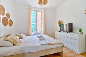 ein weißes Schlafzimmer mit einem Bett und einem Fernseher in der Unterkunft Le Cœur des Antiquaires - 5 min de Paris in Saint-Ouen + 15 Fotos
