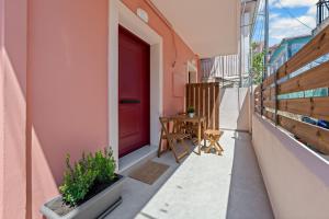 eine rote Tür an der Seite eines Gebäudes mit einem Tisch in der Unterkunft Carina Studios Lefkada 1 in Lefkada Town