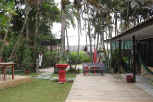 a wooden walkway in a yard with a bench and palm trees at Pousada Lua Cheia in Ilha do Mel