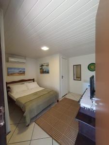 ein Schlafzimmer mit einem Bett und einem Fernseher in der Unterkunft Pousada Lua Cheia in Ilha do Mel