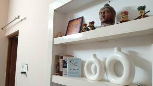 デヘラードゥーンにあるCouple Friendly Private Bedroomの2つの白い花瓶と彫像が置かれた棚