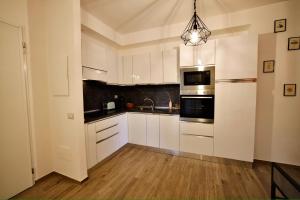 a kitchen with white cabinets and a pendant light at A casa di Sara in Ostia Antica