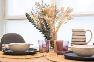 Una mesa con platos y cuencos y un jarrón con flores. en ALTZOAN Rooms Boutique & Parking, en Zarautz