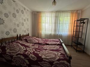 a bedroom with a bed and a window with flowers at Zindisi Forest Haven Retreat in Surami in Surami