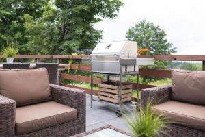 a barbecue grill on a patio with two chairs at Gruppenhaus Haus BerchStein in Winterberg