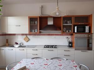 a kitchen with white cabinets and a table with chairs at All ombra del carrubo in Ottava Sassari