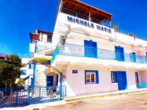 a white building with blue windows and a balcony at Michele Marie apts in Agia Pelagia +30 photos