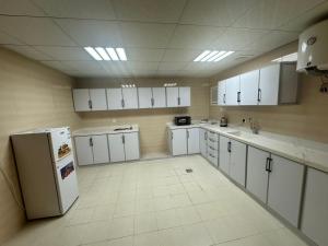 a large kitchen with white cabinets and a refrigerator at نجوم السعد 8 in Al Masfalah