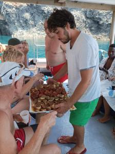a man holding a tray of food on a beach at dammuso rosa in Pantelleria