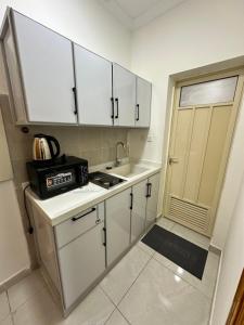 a kitchen with white cabinets and a sink at نجوم السعد 9 in Al Masfalah