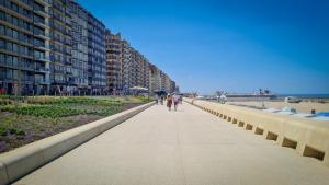 people walking down a sidewalk next to the beach at la maison de westende in Middelkerke
