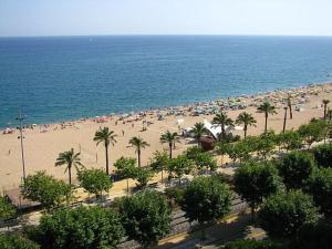 una playa con mucha gente y palmeras en Calella Can Saula III, en Calella