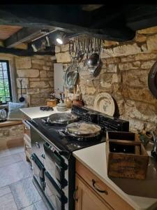 a kitchen with a stove and a stone wall at Holland Cottage in Blockley
