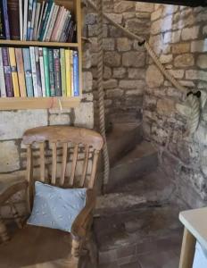 a wooden chair with a pillow next to a book shelf at Holland Cottage in Blockley