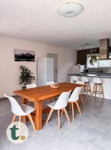 a kitchen with a wooden table and white chairs at Tranquiloue - Maison moderne - Proche PuyduFou in Mesnard-la-Barotière