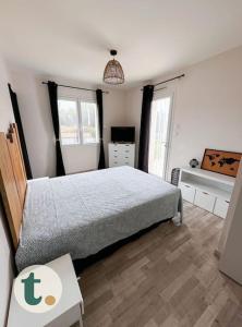 a bedroom with a bed and a table and two windows at Tranquiloue - Maison moderne - Proche PuyduFou in Mesnard-la-Barotière