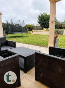 a patio with wicker chairs and tables in a park at Tranquiloue - Maison moderne - Proche PuyduFou in Mesnard-la-Barotière +19 photos