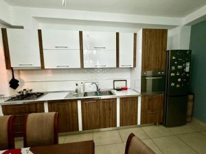 a kitchen with white cabinets and a sink and a refrigerator at Luxe Home in Shkodër