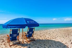 dwa krzesła i parasol na plaży w obiekcie High Pointe 1311 w mieście Seacrest
