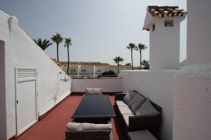 a balcony with couches and palm trees on a building at Marina de Casares Beach House in San Luis de Sabinillas