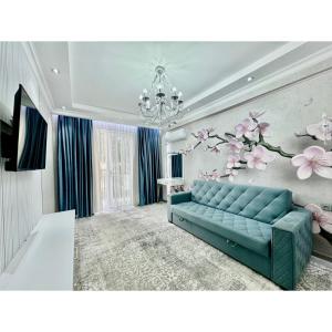 a living room with a blue couch and flowers on the wall at Classic Apartment in Tashkent