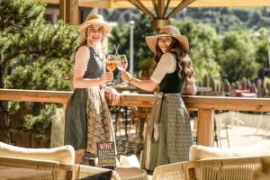 two women in hats are holding glasses of wine at B&B Berglift direkt an der Talstation in Bad Hofgastein