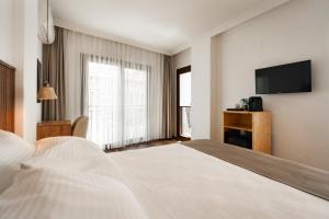 a hotel room with a bed and a flat screen tv at Rodones 1924 in Urla