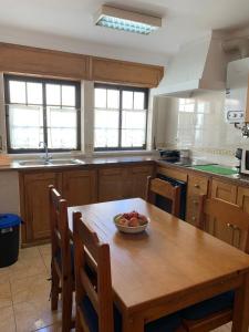 a kitchen with a wooden table with a bowl of fruit on it at Casa do Pipo in Almograve +4 photos