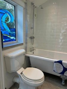 baño con aseo, bañera y ventana en Seaforth - Fisherman's Cottage, en Gorran Haven