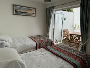 1 dormitorio con 2 camas y balcón con mesa en Seaforth - Fisherman's Cottage, en Gorran Haven 15 fotos más