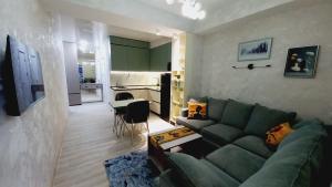 a living room with a green couch and a kitchen at Avenue Star in Tbilisi City