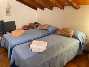 three beds with towels on them in a room at La Rosa antica dell'Etna in Puntalazzo