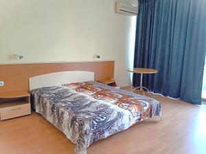- une chambre avec un lit, une table et des rideaux bleus dans l'établissement Central Avenue apartments, à Sunny Beach