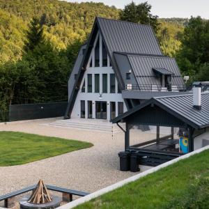 een groot wit gebouw met een zwart dak bij Hidden Chalet in Tarcău-Gheuca